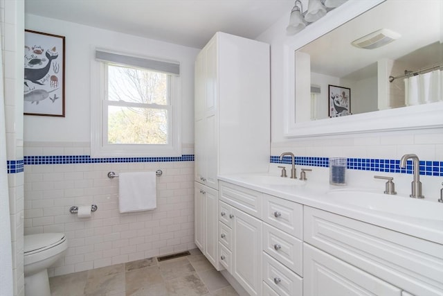 full bath with tile walls, a sink, and visible vents