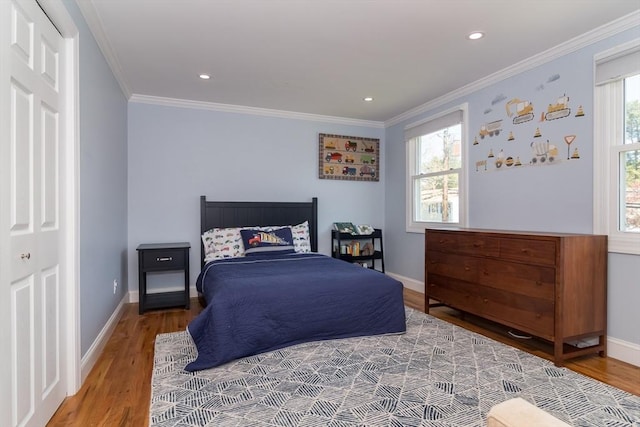 bedroom featuring crown molding, baseboards, multiple windows, and wood finished floors