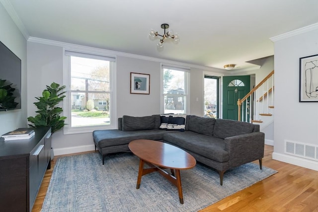 living room featuring stairway, ornamental molding, light wood-style flooring, and visible vents