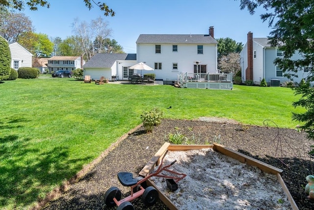 back of property featuring a chimney, a lawn, a deck, a patio area, and central AC