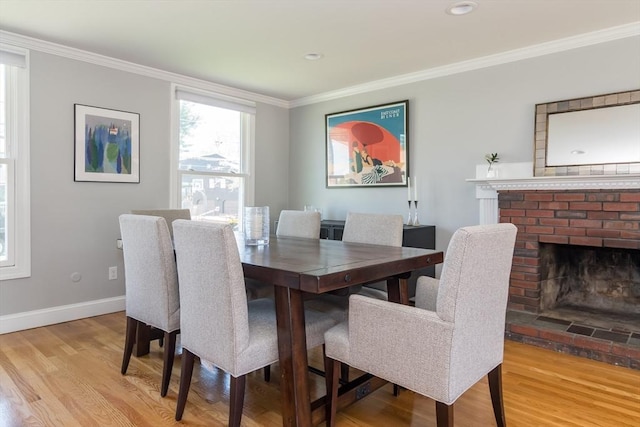 dining area with baseboards, ornamental molding, a brick fireplace, and wood finished floors