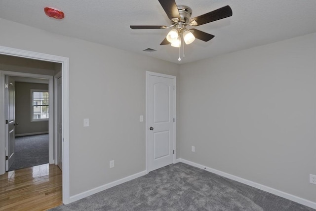 unfurnished bedroom with dark colored carpet and ceiling fan