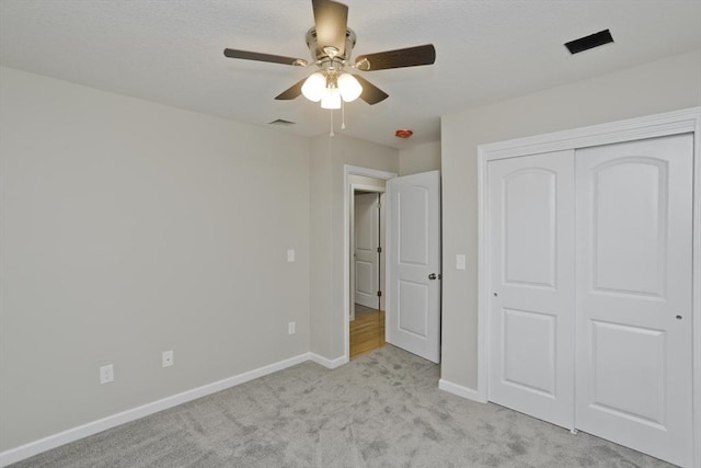 unfurnished bedroom featuring light carpet, a closet, and ceiling fan