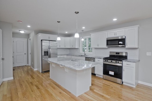 kitchen featuring pendant lighting, a center island, white cabinets, light wood-type flooring, and appliances with stainless steel finishes