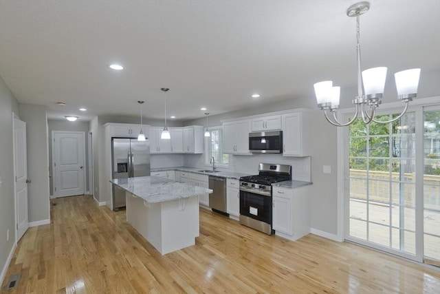 kitchen with pendant lighting, a center island, light hardwood / wood-style floors, white cabinetry, and stainless steel appliances