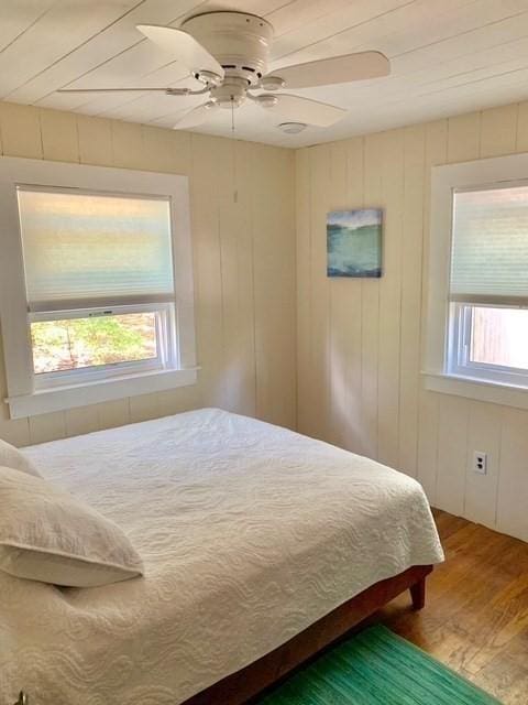 bedroom with a ceiling fan, multiple windows, and wood finished floors