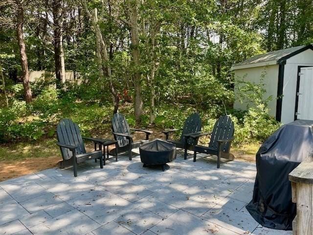 view of patio / terrace with an outbuilding, a shed, grilling area, and a fire pit