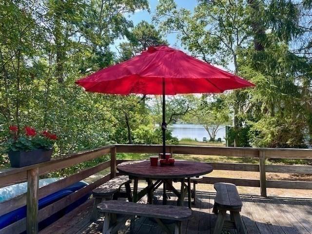 wooden deck with a water view and outdoor dining space