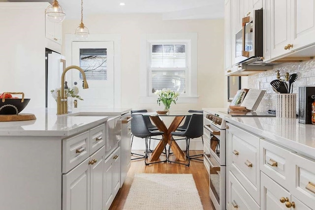 kitchen featuring decorative light fixtures, light hardwood / wood-style floors, white cabinetry, and white range with electric stovetop