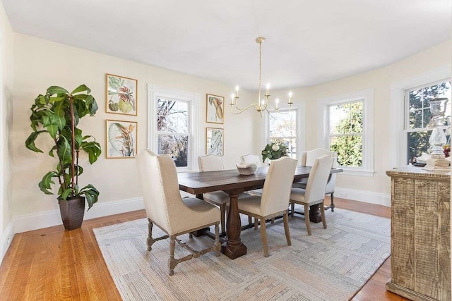 dining space with light hardwood / wood-style flooring, plenty of natural light, and a notable chandelier