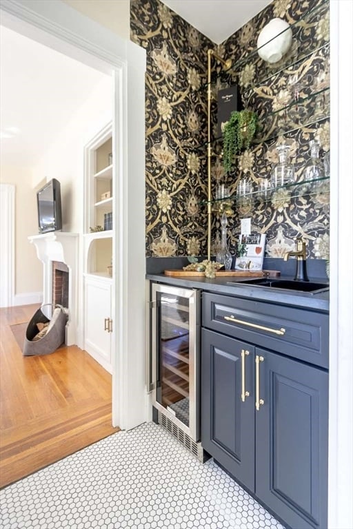 bar with blue cabinetry, light wood-type flooring, wine cooler, and sink