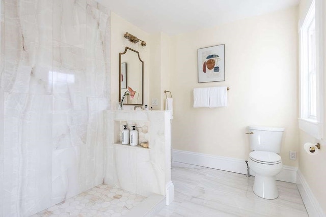 bathroom with a tile shower and toilet