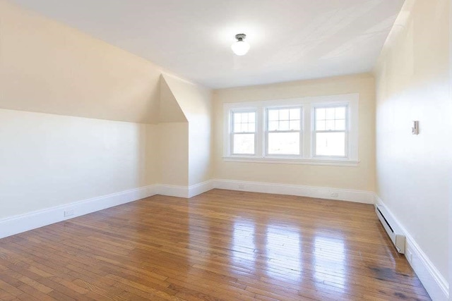 additional living space with light hardwood / wood-style flooring and a baseboard heating unit