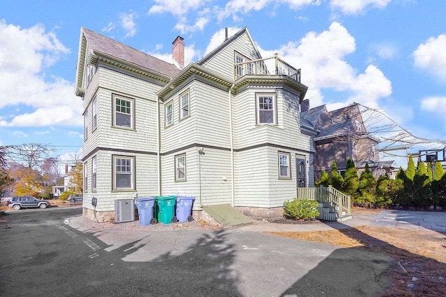 back of property with cooling unit and a balcony