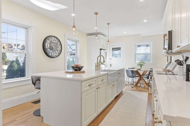 kitchen featuring a wealth of natural light, a center island with sink, and sink