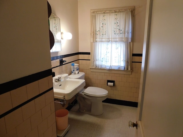 bathroom with sink, tile patterned flooring, toilet, and tile walls