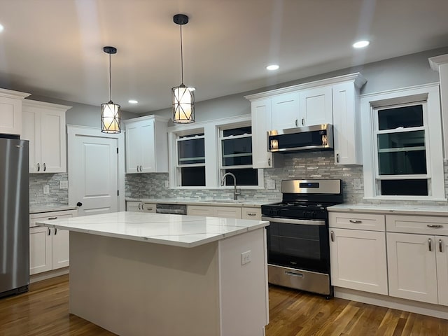 kitchen with stainless steel appliances, white cabinetry, dark wood-type flooring, and a center island