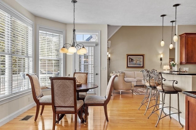 dining area with light wood-type flooring and a notable chandelier