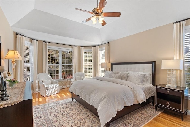 bedroom with ceiling fan, light hardwood / wood-style flooring, and a tray ceiling