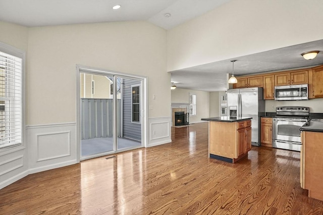 kitchen with a center island, decorative light fixtures, dark countertops, appliances with stainless steel finishes, and brown cabinetry