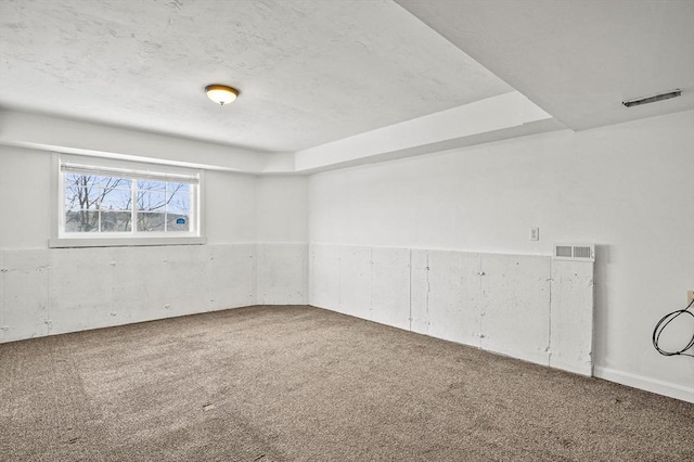 carpeted empty room featuring visible vents and a textured ceiling