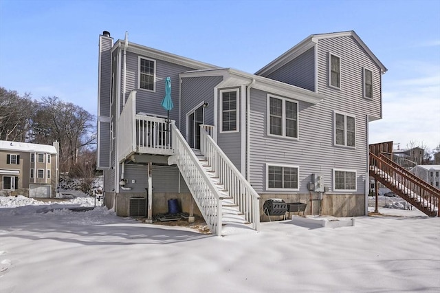 snow covered property featuring stairs and central AC unit