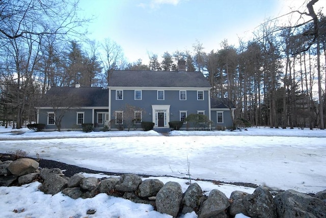 snow covered back of property featuring a chimney