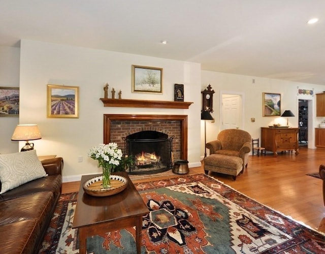 living room featuring recessed lighting, a fireplace, baseboards, and wood finished floors