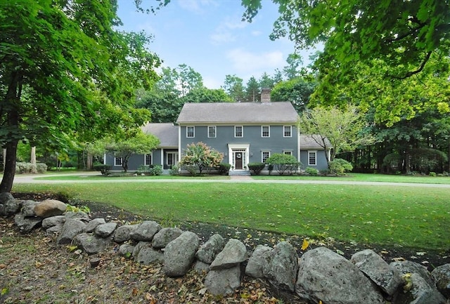 colonial-style house with a chimney and a front lawn