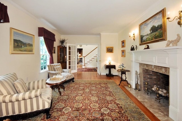 living area featuring stairway, a fireplace with flush hearth, wood finished floors, and ornamental molding