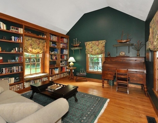 living area featuring visible vents, lofted ceiling, and wood finished floors