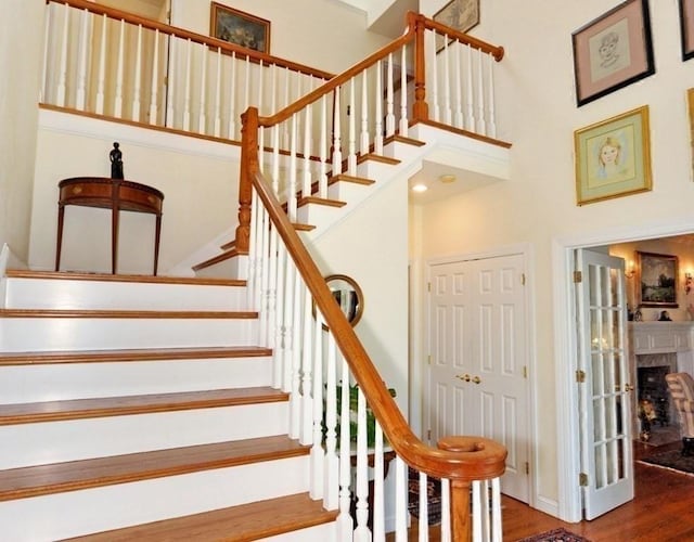 stairs with wood finished floors, a high ceiling, and a fireplace