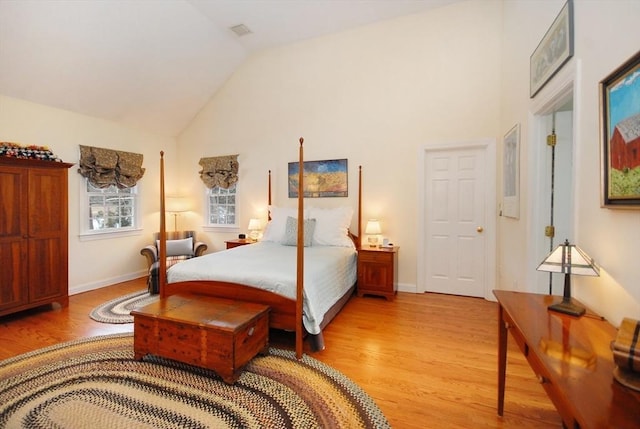 bedroom featuring baseboards, light wood finished floors, and high vaulted ceiling