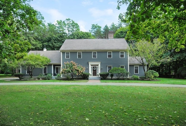 colonial home with a chimney and a front yard