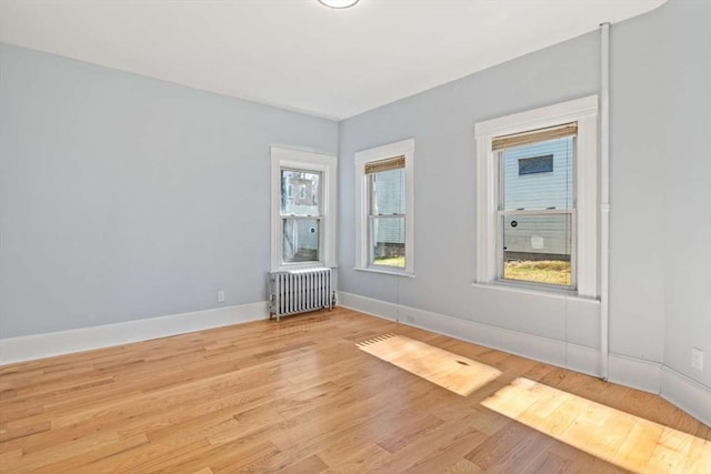 unfurnished room featuring radiator and light hardwood / wood-style flooring