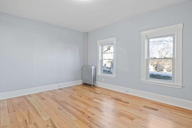 spare room with radiator heating unit and light hardwood / wood-style flooring