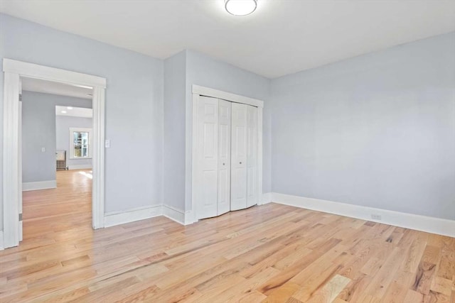 unfurnished bedroom with light hardwood / wood-style flooring and a closet