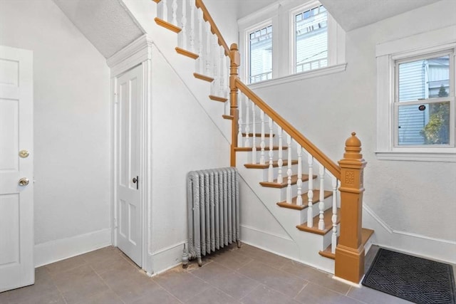 stairs featuring tile patterned flooring, plenty of natural light, and radiator heating unit