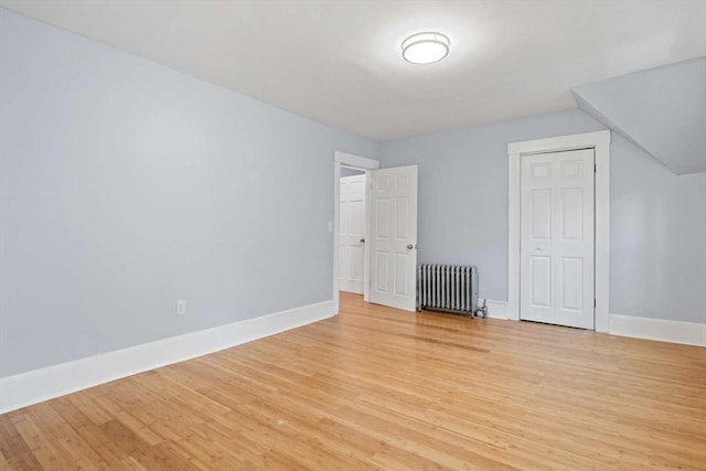 bonus room with light wood-type flooring and radiator heating unit