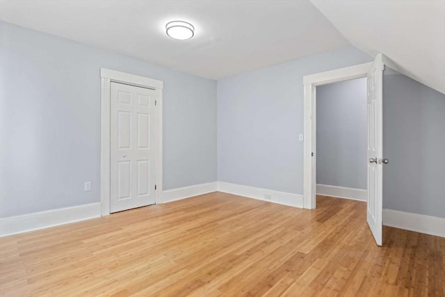 spare room featuring vaulted ceiling and light wood-type flooring