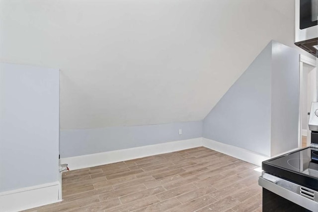 additional living space featuring light wood-type flooring and lofted ceiling