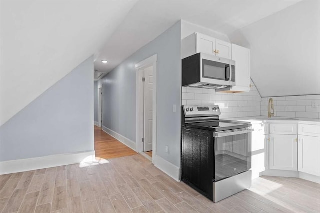 kitchen with light hardwood / wood-style floors, white cabinetry, sink, and appliances with stainless steel finishes