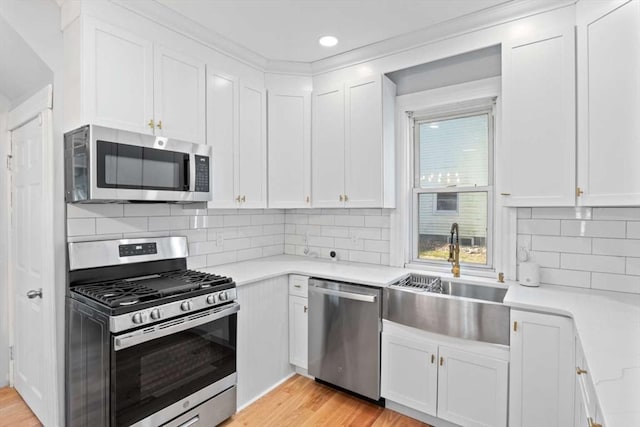 kitchen with white cabinets, light wood-type flooring, sink, and appliances with stainless steel finishes