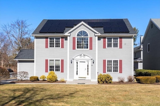 colonial home with solar panels and a front yard