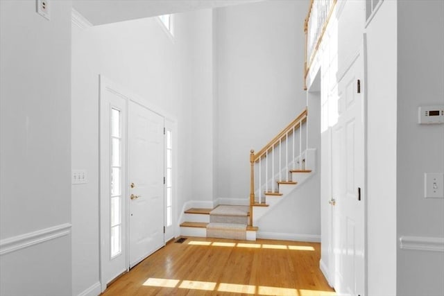 foyer entrance featuring stairs, wood finished floors, baseboards, and a towering ceiling