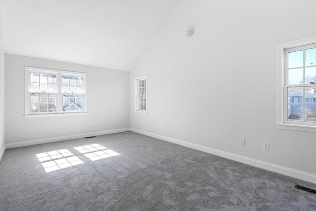 carpeted spare room with visible vents, baseboards, and vaulted ceiling