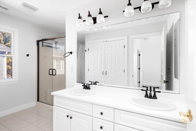 full bath with double vanity, visible vents, a shower stall, and a sink