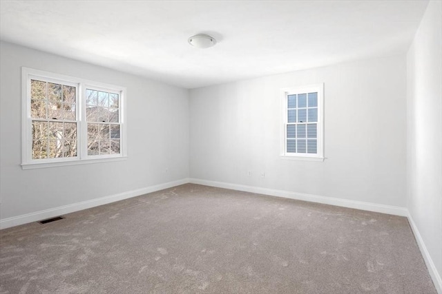 spare room with carpet flooring, baseboards, and visible vents