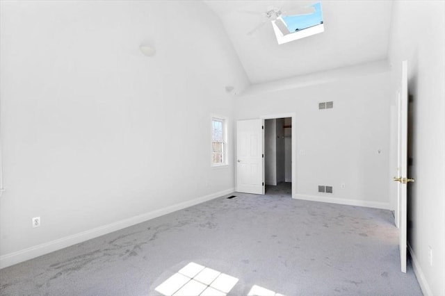 interior space featuring visible vents, baseboards, a skylight, and carpet flooring