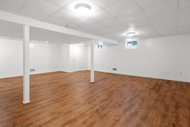 basement with wood finished floors, baseboards, and a paneled ceiling